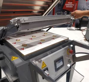 A worker operates a fixed oven manual skin packaging machine